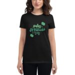 A person is wearing a black t-shirt featuring the text Happy St Patrick's Day in green with decorative elements in a festive setting celebrating the holiday.