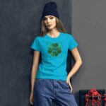 A young woman stands confidently wearing a bright turquoise t-shirt with a green shamrock design and the text "Happy St. Patrick's Day" in a textured gray backdrop with chains.