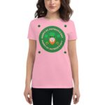 A woman is wearing a pink t-shirt featuring a green circular design that says "HAPPY ST. PATRICK'S DAY" with an illustration of a leprechaun and shamrocks surrounding it.