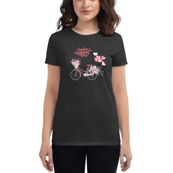 A woman wears a dark shirt featuring a pink bicycle adorned with flowers and hearts celebrating Valentine's Day. The shirt emphasizes a festive and cheerful theme suitable for the occasion.