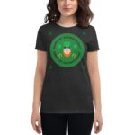 A woman wears a dark t-shirt featuring a green circular design with a leprechaun face and text that reads Happy St. Patrick's Day surrounded by shamrock icons in a festive context.