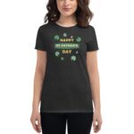 A woman is wearing a black t-shirt displaying green shamrocks and the text "HAPPY ST. PATRICK'S DAY" in yellow and green surrounded by small shamrocks in a casual setting.