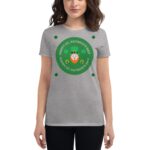 A woman wearing a gray t-shirt displays a green circular design featuring a leprechaun and clovers that reads HAPPY ST. PATRICK'S DAY multiple times in a festive context.