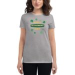 A woman wears a gray t-shirt featuring a green clover design with the text HAPPY ST. PATRICK'S DAY prominently displayed  celebrating the holiday in a casual  festive context.