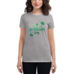 A woman wears a gray t-shirt featuring festive green text that reads Happy St. Patrick's Day surrounded by shamrocks and sparkles highlighting the celebration of the holiday.