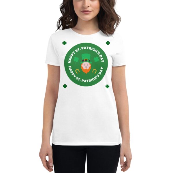 A woman wearing a white t-shirt with a green circular design featuring a leprechaun and text that says Happy St. Patrick's Day surrounded by four shamrocks against a neutral background.