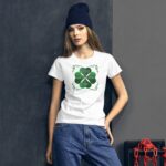 A woman stands confidently wearing a white t-shirt with a green shamrock design that says Happy St. Patrick's Day while casually dressed in jeans against a dark background with a red chain.