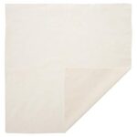 A square piece of off-white fabric lies flat on a surface with one corner folded over exposing a lighter shade underneath in a simple indoor setting.