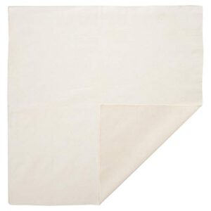 A square piece of off-white fabric lies flat on a surface with one corner folded over exposing a lighter shade underneath in a simple indoor setting.