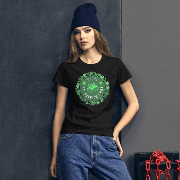A woman is wearing a black t-shirt with a green graphic that says "Happy St. Patrick's Day" surrounded by shamrocks in front of a textured dark background.