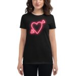 A person wears a black t-shirt featuring a neon pink heart design with an arrow through it  standing against a plain background  highlighting the shirt's graphic element.