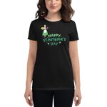 A person wears a black t-shirt featuring a cartoon character with a green dress holding a yellow item text reads HAPPY ST. PATRICK'S DAY surrounding it are decorative four-leaf clovers.