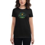 A black t-shirt worn by a woman displays the text "my first St. Patrick's Day" with decorative green elements and shamrocks  highlighting a festive occasion in a casual setting.