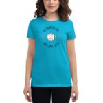 A woman wears a bright blue t-shirt featuring a graphic of a smiling coffee cup surrounded by hearts with the text "ALL YOU NEED IS LOVE AND A CUP OF COFFEE" in a playful font.