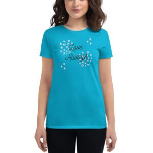 A woman is wearing a bright turquoise t-shirt with the text "Love Always" printed in black  surrounded by decorative elements  while standing against a plain white background.