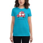 A woman wearing a bright turquoise t-shirt stands displaying a graphic of a red cartoon truck with two gnomes holding hearts and a message that reads Happy Valentine's Day.