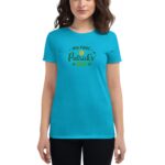 A blue t-shirt worn by a woman features the text "my first St Patrick's Day" in decorative lettering with small graphics  indicating celebration and festive spirit in a casual setting.