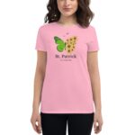 A woman wears a pink t-shirt showcasing a green butterfly  sunflowers  and text reading St. Patrick it’s a Lucky Day  standing in a neutral setting.