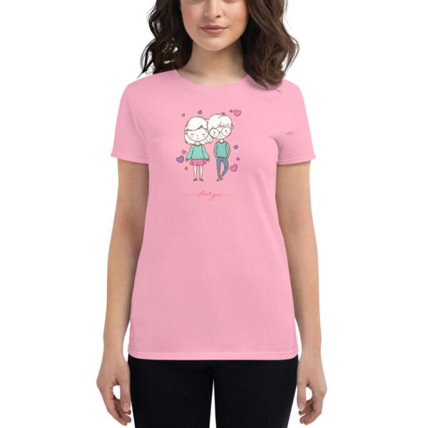 A woman wearing a pink t-shirt stands  displaying a printed design of two cartoon characters in love surrounded by hearts with the text love you below them