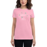 A woman is wearing a pink t-shirt featuring the text LUCKY HAPPY ST. PATRICK'S DAY surrounded by green shamrocks and stars representing a festive St. Patrick's Day theme.