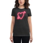 A woman wears a dark t-shirt featuring a neon pink heart design with an arrow  smiling against a plain background  showcasing a casual and trendy clothing style.