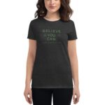 A woman stands wearing a dark T-shirt with the text “BELIEVE YOU CAN” and “HAPPY ST. PATRICK'S DAY” in green  promoting positivity and celebrating the holiday.