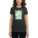 A woman stands wearing a dark shirt featuring a vibrant graphic design that reads "DO WHAT MAKES YOU HAPPY" with festive elements for St. Patrick's Day.