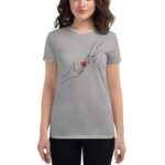 A woman is wearing a gray t-shirt featuring a line drawing of two hands reaching towards each other with a small red heart between them  set against a plain background.