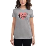 A woman is wearing a gray t-shirt featuring the word love in a stylish script inside a pink heart against a neutral background.
