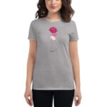 A woman wears a grey t-shirt featuring a pink rose  lips  and a design with the year 2024 below  presented in a casual indoor environment.