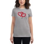 A woman wears a gray t-shirt adorned with two intertwined red hearts made of flowers and the year 2024 below them  standing against a plain background.