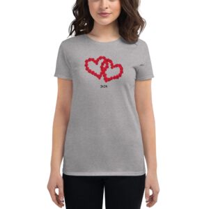 A woman wears a gray t-shirt adorned with two intertwined red hearts made of flowers and the year 2024 below them  standing against a plain background.