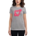 A woman stands wearing a gray t-shirt featuring a neon red heart with an arrow through it  showcasing a playful and stylish design in a casual setting.