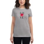 A woman wears a grey t-shirt featuring the word "LOVE" in black letters with a red flower in the center amid a neutral background.