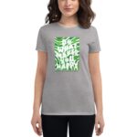 A woman wears a gray T-shirt featuring a green and white design with text that says do what makes you happy and happy St Patrick's Day set against a casual backdrop.
