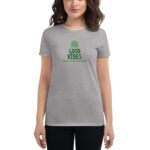 A person wears a light gray t-shirt featuring green text that states GOOD VIBES and HAPPY ST.PATRICK'S DAY surrounded by a decorative rainbow design against a simple background.