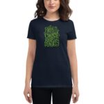 A woman wears a dark t-shirt featuring vibrant green text that reads "YOU HAVE THE COURAGE TO BEGIN AGAIN" alongside "HAPPY ST. PATRICK'S 2023". She has medium-length wavy hair.