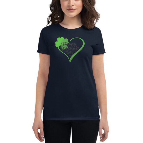 A woman stands wearing a dark navy t-shirt adorned with a green heart and a shamrock featuring the text Happy St Patrick's Day  indicating a festive celebration context.