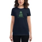 A woman wears a dark navy t-shirt featuring a graphic that says "GOOD VIBES" with a rainbow and "HAPPY ST. PATRICK'S DAY" in green text  standing in a casual setting.
