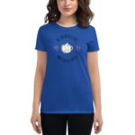 A woman stands wearing a bright blue t-shirt featuring a cartoon coffee cup with a smile and the text all you need is love and a cup of coffee surrounded by hearts.