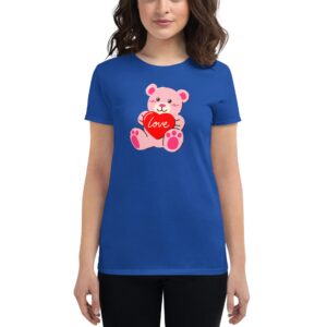 A blue t-shirt features a cute pink teddy bear holding a red heart with the word love on it while being worn by a smiling woman with dark hair in a neutral setting.