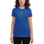 A woman stands wearing a blue t-shirt featuring green text that reads GOOD VIBES and HAPPY ST. PATRICK'S DAY with a rainbow graphic above.