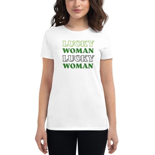A woman wears a white t-shirt featuring the text LUCKY WOMAN in various styles and colors  standing against a neutral background with a relaxed expression.