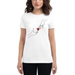 A woman wears a white t-shirt featuring simple black line drawings of two hands reaching toward each other with a small red heart between them  set against a plain background.