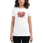 A woman is wearing a white t-shirt featuring the word love in stylish black cursive letters against a soft pink heart background  standing in a neutral setting.