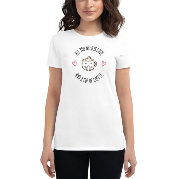 A person wearing a white t-shirt displays a graphic featuring a smiling coffee cup surrounded by hearts with the text reading all you need is love and a cup of coffee.