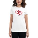 A woman wears a white t-shirt featuring two intertwined red hearts and the year 2024 printed below. She stands confidently in a neutral setting  showcasing the design prominently.