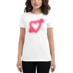 A woman is wearing a white t-shirt featuring a neon red heart design with an arrow. She is standing against a plain white background.