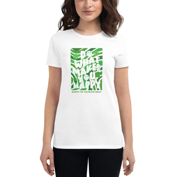 A woman wears a white t-shirt featuring green text that reads "DO WHAT MAKES YOU HAPPY" with a smiling face and shamrocks  celebrating St. Patrick's Day.