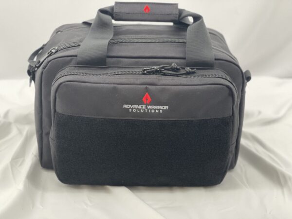 A black tactical bag with two zipped compartments features a soft velcro patch on the front and carries the logo of Advance Warrior Solutions against a light backdrop.